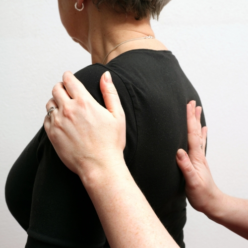 Female therapist applies pressure to a patients middle back in order to alleviate pain.